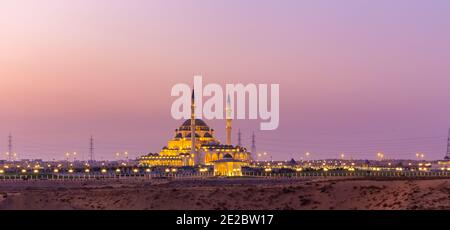 New Sharjah Mosque, the largest mosque in the Emirate of Sharjah, the United Arab Emirates, panorama with pink sky sunset background. Stock Photo