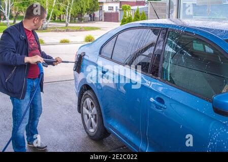 A man washes a car on his own. Car wash self-service. Cheap car wash.Man washing his car in a self-service car wash station Stock Photo