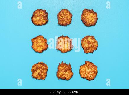 Homemade potato pancakes aligned symmetrically in a square on a blue background. Fried potato pancakes above view. Stock Photo