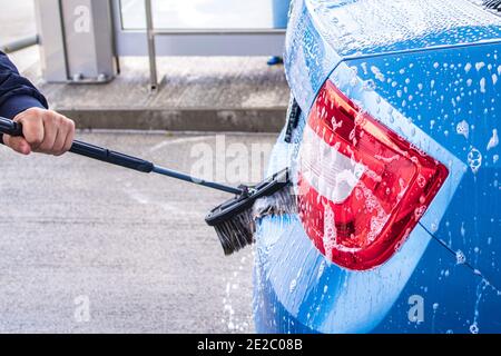 A man washes a car on his own. Car wash self-service. Cheap car wash.Man washing his car in a self-service car wash station Stock Photo
