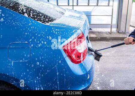 A man washes a car on his own. Car wash self-service. Cheap car wash.Man washing his car in a self-service car wash station Stock Photo