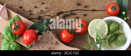 Italian Mediterranean cuisine with different vegetables, tomatoes, olive oil, spice, garlic on old wooden background. Fresh ingredients for pizza, pas Stock Photo