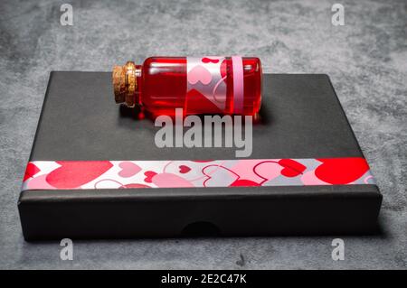 Close-up image of a love potion in a glass stopper bottle on top of a gray paper gift box Stock Photo