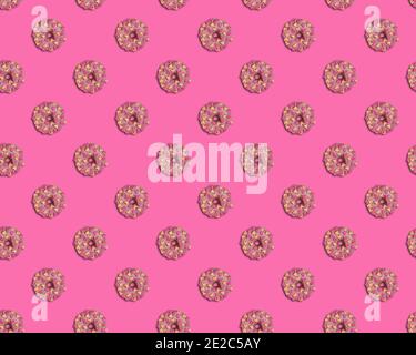 Seamless pattern with beautiful doughnuts glazed with pink chocolate and peach and pink colored marshmallow hearts on pink background. View from direc Stock Photo