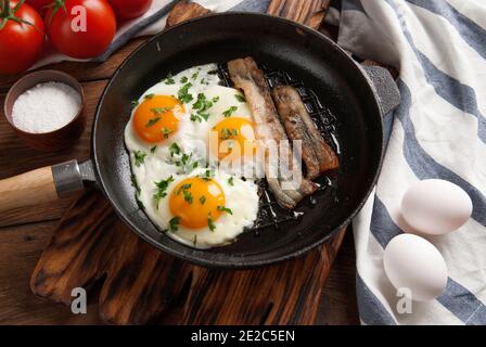 Scrambled eggs and bacon in a small pan on the kitchen table Stock Photo