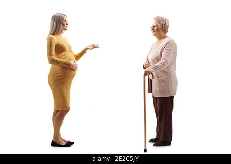 Full length profile shot of a pregnant woman talking to an elderly woman isolated on white background Stock Photo