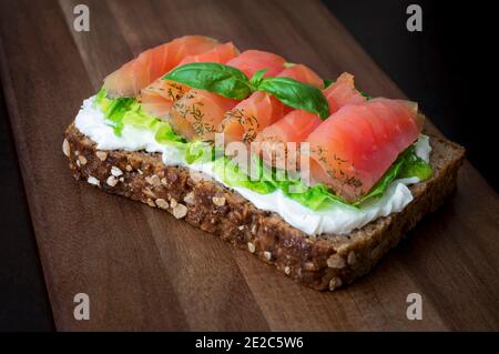 Smoked salmon sandwich with fresh lettuce and cheese cream. Healthy nutrition receipt.  Sandwich   with homemade brown bread and smoked salmon suitabl Stock Photo