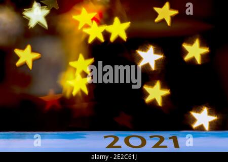 The golden inscription 2021 on a celestial background against a dark background with bokeh of star-shaped lights Stock Photo