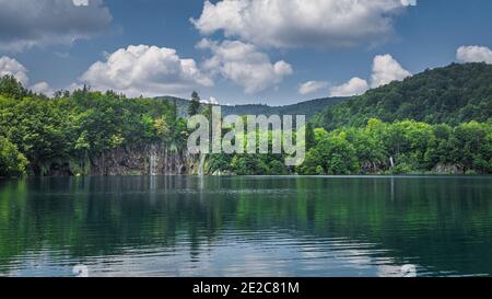 Panoramic view on beautiful waterfalls with reflections in lake. Green lush forest, Plitvice Lakes National Park UNESCO World Heritage in Croatia Stock Photo