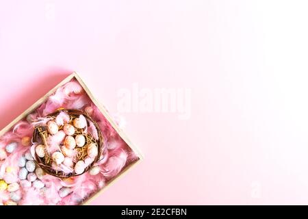 Easter composition with traditional decor. Small decorative colorful eggs and soft feathers in a basket Stock Photo