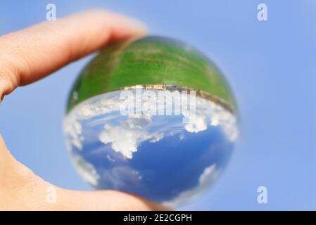 cloudy sky which is reflected in a Lens Ball.Horizon, green field. the world is upside down, on the contrary. new reality, new life Stock Photo