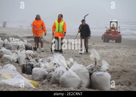 Clean-up crews hard at work cleaning the shores on Papamoa Beach in Tauranga, New Zealand, on October 13, 2011. The 47,000 tonne Rena, a Liberan container vessel, struck a reef on Wednesday causing an oil leak that has spread over five kilometres. Authorities are preparing for the worst environmental disaster in New Zealand history should the vessel break up and spill 1,700 tonnes of fuel into the Bay of Plenty. Photo by Maritime New Zealand/ABACAPRESS.COM Stock Photo