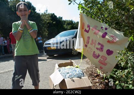 A little boy wearing bracelets with the inscription I'm Gilad too ties a  yellow ribbon (symbol of the struggle to free Gilad Shalit) in the olive  trees in the house of Shalit's