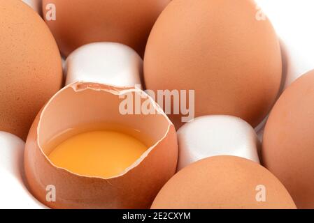 Broken egg with yolk among whole eggs. Close up. Stock Photo