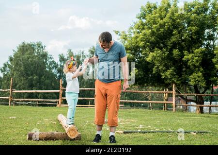active games outdoors. Father playing with his baby girl in the park. Countryside, walk along rural road.Leads his little daughter, holds the hand, Stock Photo