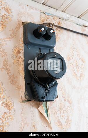 Belarus, Bakshti - January 10, 2021: Home vintage country house electricity meter hanging on the wall Stock Photo
