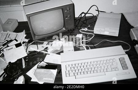 A sloppy home work station in the 1980s, featuring a Commodore 64 Computer hooked up to a black and white TV, 5 1/4 inch floppy drive, a 300 Baud Modem, and a dot-matrix printer Stock Photo