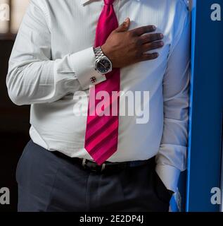 African businessman in a classic white shirt wearing a watch with his hand on his heart Stock Photo