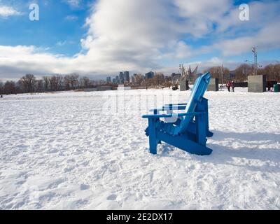 January 09, 2021 - Montreal, Canada Outdoors chairs in the snow at Park Jean-Drapeau in winter with Montreal buildings in the background Stock Photo
