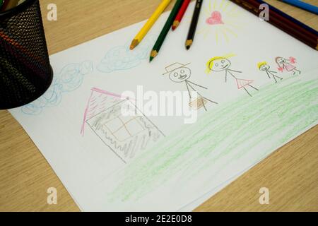 Kids Drawing Of Family And Colored Pencils On Wooden Table Stock