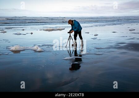 WA19121-00...WASHINGTON - Photographer Tom Kirkendall photographing sea foam on Long Beach. Stock Photo