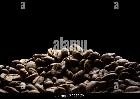 Coffee beans freshly roasted close-up with black background for text space. Stock Stock Photo