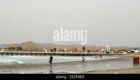 Pier and beach in cerro Azul surfers and mountains behind. Stock Photo