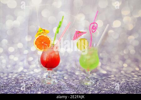 Two glasses with bright fruit drinks and slices of citrus lime and grapefruit on a gray shiny background. Close-up. Stock Photo