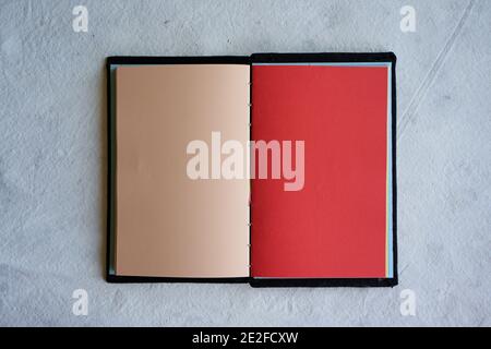 Top view of an open notebook with blank cream and red sheets placed on a white surface Stock Photo