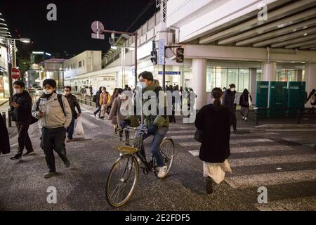 Kawasaki, Japan. 13th Jan, 2021. A man on a bike wearing a facemask near Keikyu Kawasaki Station. Credit: SOPA Images Limited/Alamy Live News Stock Photo