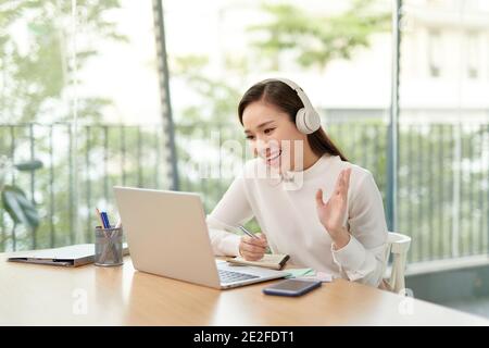 Sweet girl working on laptop with headset on her head. Having fun and surfing over the internet. Stock Photo
