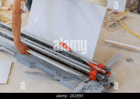Man working at the cut ceramic tile on the manual tile cutting Stock Photo