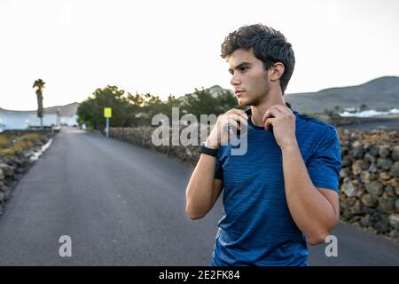 Young Caucasian man holding his headphones in the street Stock Photo