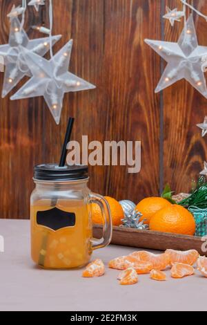 Freshly squeezed tangerine juice in jar with handle and free label for your text. Citrus fruits in winter composition. Blurred background, selective f Stock Photo