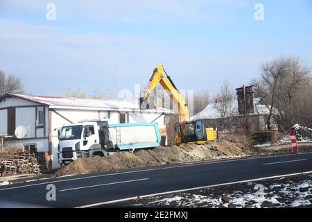 Large excavator filling a dump truck with rock and soil for road repairs.  Stock Photo