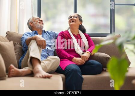 A SENIOR COUPLE SITTING TOGETHER AND LAUGHING HAPPILY Stock Photo