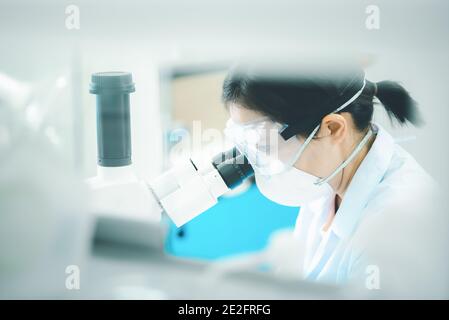 Doctor or scientist looking through a microscope in medical research lab or science laboratory. Stock Photo