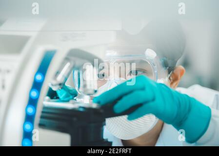 Doctor or scientist looking through a microscope in medical research lab or science laboratory. Stock Photo