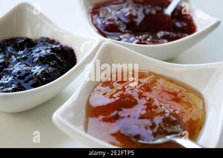 A selection of three different jams in little white bowls. Stock Photo