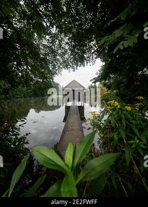 Wooden walkway leading to old boat house on lake Muehlteich Muhlteich Woerthersee Moosburg Carinthia Austria in Europe Stock Photo