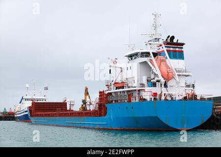 General Cargo Ship with blue hull is moored in port of Reykjavik, stern view Stock Photo