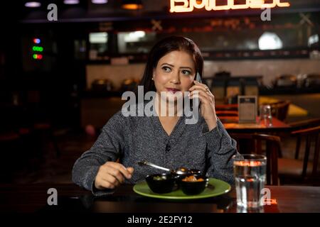Portrait of a pretty woman conversing on the phone while sitting in a restaurant. Stock Photo
