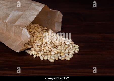 Bag of pine nuts on wooden table. Scattered nuts. Healthy snack concept Stock Photo