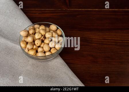 Roasted hazel nuts in a bowl on rustic background. Scattered nuts Stock Photo