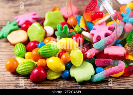 Various colorful candies, jellies and marmalade in glass jar on wooden table Stock Photo