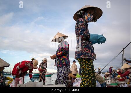 Men and women working at a fish Market on the beach, Mui Ne, Vietnam Stock Photo