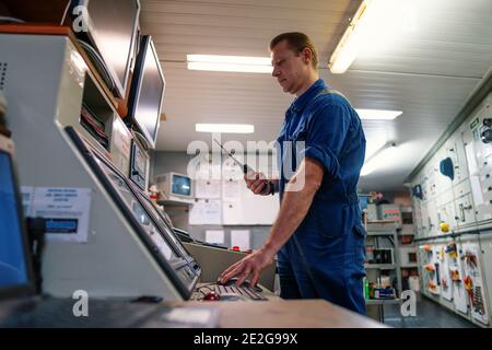 Marine Engineer working on radio communication at Engine Control room ECR Stock Photo