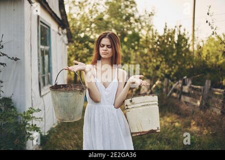 how was it a happy woman with buckets near a building in a nature farm village Stock Photo