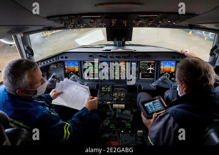 Kyiv, Ukraine - November 25, 2020: Embraer aircraft cockpit. Pilots in medical masks. Technicians diagnose, repair and service the aircraft. Workers w Stock Photo