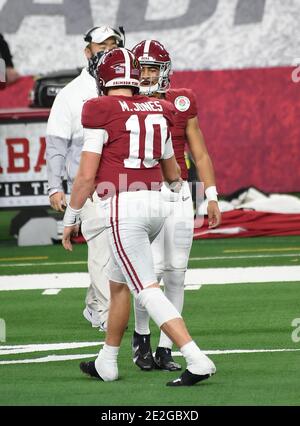 Alabama quarterback Mac Jones, right, holds a team jersey with NFL  Commissioner Roger Goodell a …